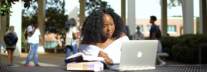 Student outside of Humanities Building working on computer